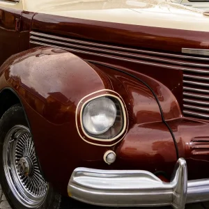 Carro-classico-com-pintura-colorida-em-primeiro-plano-destacando-cromados-e-acabamento-vintage.