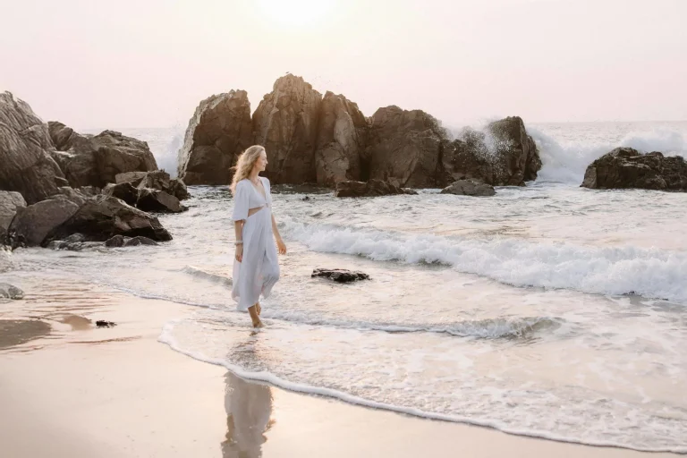 Mulher-caminhando-sozinha-na-praia-com-o-reflexo-do-corpo-espelhado-entre-a-agua-e-a-areia-simbolizando-reflexao-consciencia-e-mudanca-de-mentalidade.